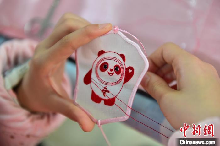 圖為一名小學(xué)生正在繡制2022年北京冬奧會(huì)吉祥物“冰墩墩”形象?！∮髟屏?攝