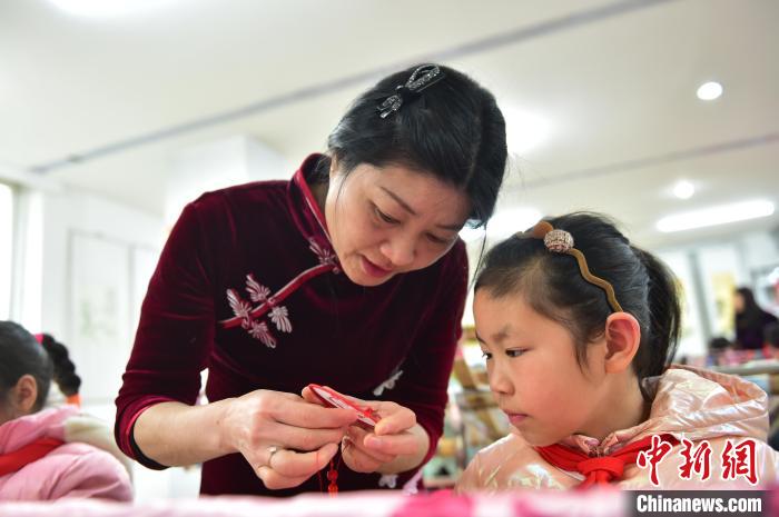 江西省級(jí)非遺豫章繡傳承人手把手指導(dǎo)小學(xué)生繡制2022年北京冬奧會(huì)吉祥物“冰墩墩”形象。　喻云亮 攝
