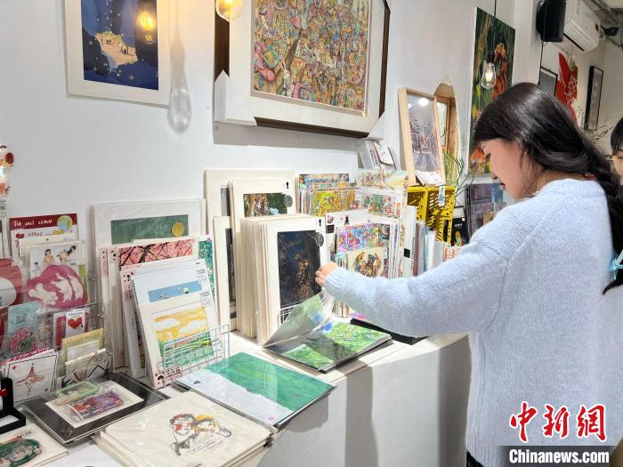 圖為藝術(shù)品商店內(nèi)，顧客挑選插畫作品?！＄婌?攝