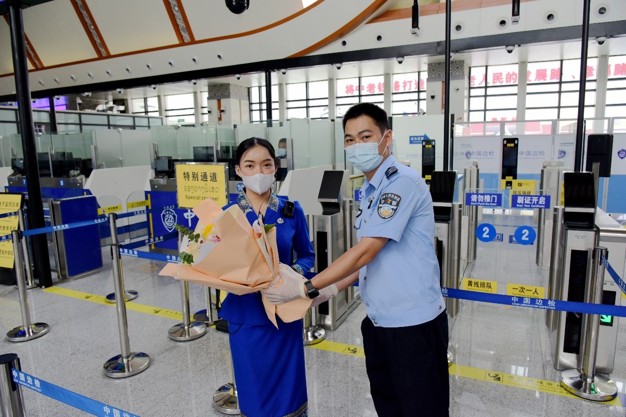 磨憨出入境邊防檢查站民警為中老鐵路第100萬名出入境旅客，D888次國際旅客列車?yán)蠐爰藙?wù)員森達(dá)拉·妮緹婭（Sengdala Nitiya），送上鮮花。黃遠(yuǎn)飛 攝