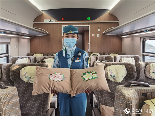 趙瑩靜展示中老鐵路國際旅客列車?yán)飵в兄袊档せê屠蠐胝及突ù汤C圖案的靠墊。人民網(wǎng)記者 杜明明攝