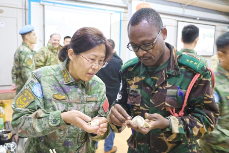 圖為維和官兵與外軍人員共同包餃子。胡光明攝