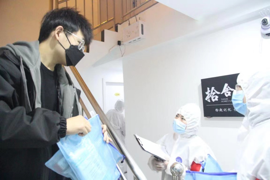 社區(qū)工作人員和志愿者身穿防護(hù)服上門(mén)送馬應(yīng)龍大健康防疫包。徐帥攝