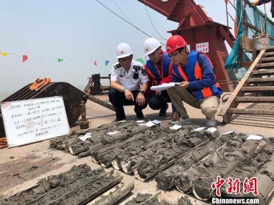 圖為勘察設(shè)計人員與海事局工作人員查看巖芯情況。　魏震 攝