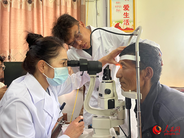 王紅英（左）和團隊成員為達熱村村民檢查眼睛。人民網(wǎng)記者 杜燕飛攝