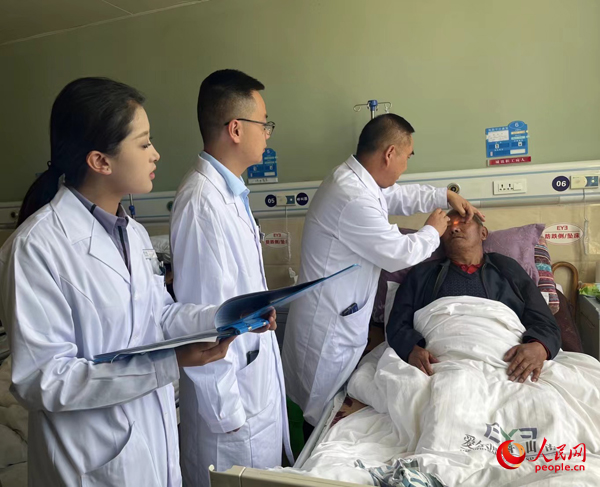 董光明（左三）帶領醫(yī)生對患者進行術前檢查。人民網(wǎng)記者 杜燕飛攝