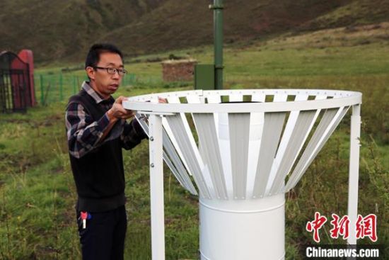 圖為班瑪縣氣象局工作人員在維護(hù)藏雪茶基地氣候站。青海省氣象局供圖