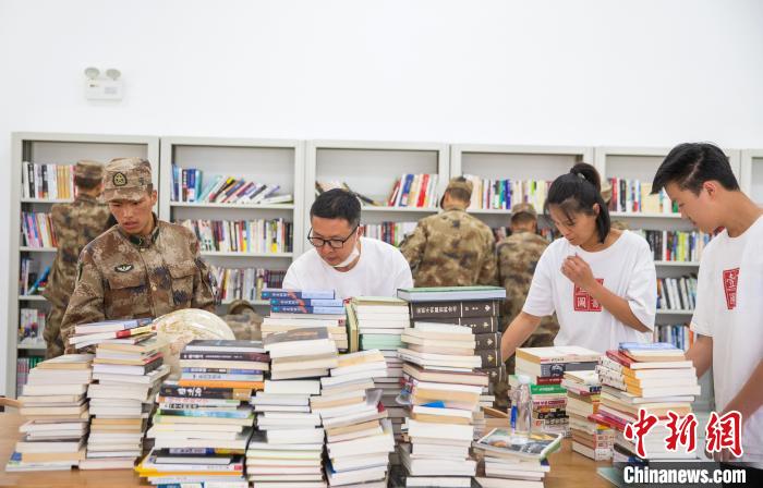 圖為志愿者們和邊防戰(zhàn)士整理圖書?！詵| 攝