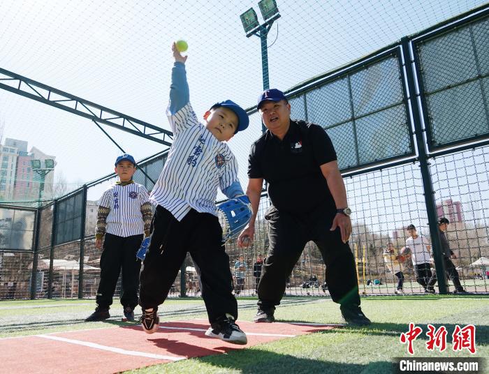 圖為來自臺灣的棒球教練劉興鴻(右)指導(dǎo)小棒球手?jǐn)S球技術(shù)?！●R銘言 攝