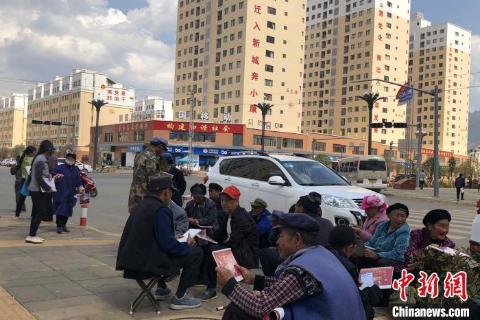圖為會澤縣城易地扶貧搬遷安置點內，老人們聚在廣場上聊天，身后是他們的新家。　繆超 攝
