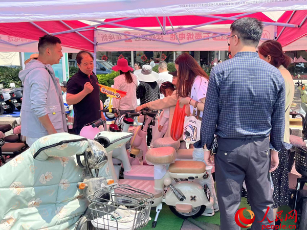 某電動自行車品牌工作人員向消費者介紹以舊換新相關情況。人民網(wǎng)記者 杜燕飛攝