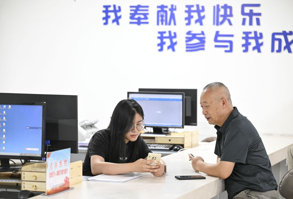 2024年6月20日，在寧夏銀川市金鳳區(qū)長(zhǎng)城花園社區(qū)黨群服務(wù)中心，工作人員幫助居民辦理業(yè)務(wù)。圖片來(lái)源 新華社