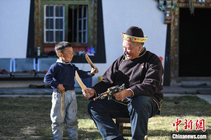 圖為米林縣扎西繞登鄉(xiāng)彩門村64歲的洛桑帶著孫子巴桑在院子的草地上玩耍。　何蓬磊 攝