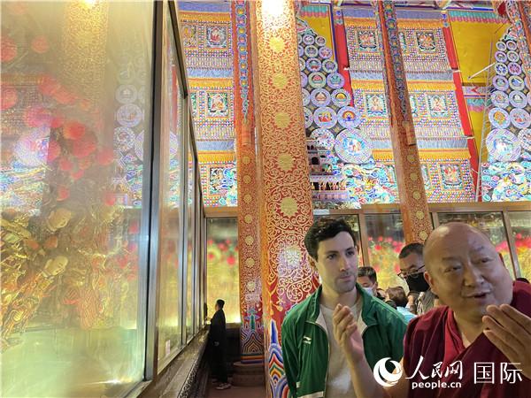 7月25日，省級非物質(zhì)文化遺產(chǎn)項(xiàng)目塔爾寺酥油花的代表性傳承人朋措堅(jiān)參（右）在塔爾寺酥油花館講解酥油花的制作過程。人民網(wǎng) 謝瑩攝