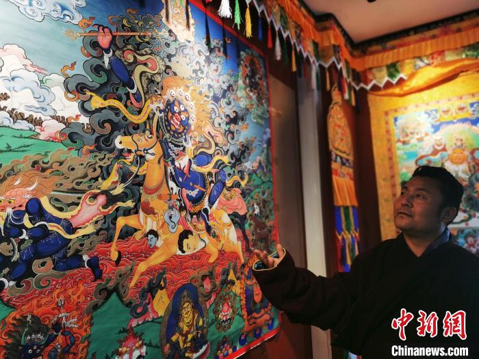 圖為久美尖措展示唐卡作品?！?zhí)砀?攝