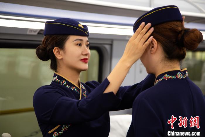 圖為青藏鐵路西格段“復(fù)興號”動車組乘務(wù)員互相整理新制服?！±罾?攝