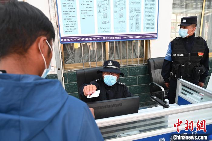 圖為移民管理警察登記完身份信息后將證件歸還給行人?！≮w朗 攝