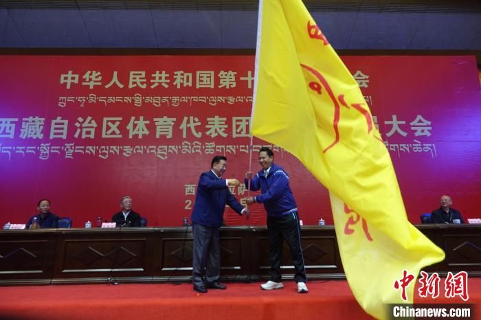 西藏自治區(qū)副主席甲熱·洛桑丹增授代表團團旗，西藏自治區(qū)體育局局長尼瑪次仁接旗?！∪轿木?攝