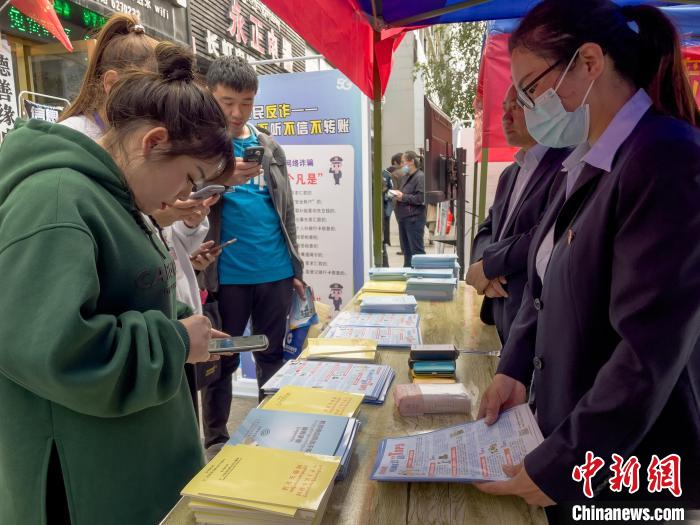 圖為工作人員正在向路過市民介紹國家反詐中心軟件的功能?！≈x牧 攝