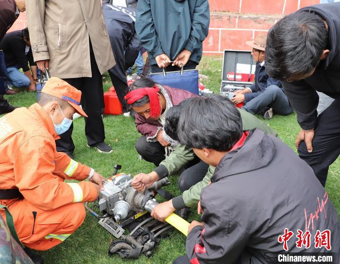 圖為森林消防員為護(hù)林員講解滅火裝備的使用方法?！〔际猩窒乐ш?duì) 供圖