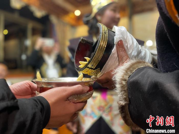 圖為主人在碗中斟滿青稞酒?！∪轿木?攝
