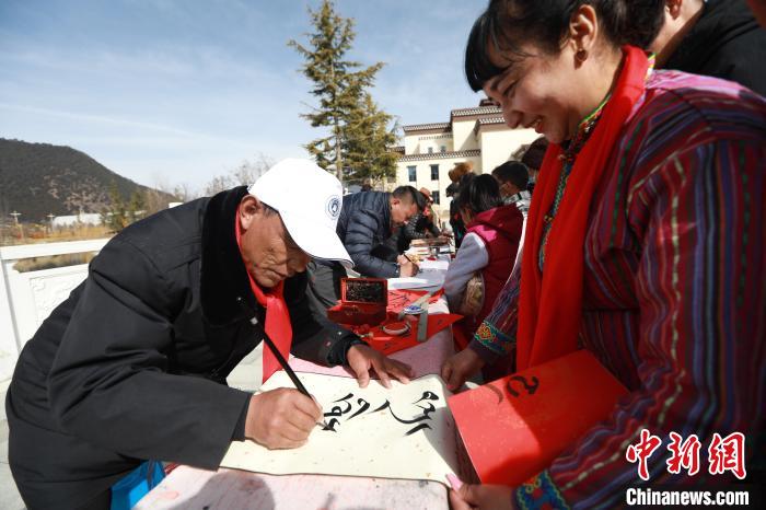 圖為林芝市文聯(lián)書(shū)法家協(xié)會(huì)會(huì)員向民眾贈(zèng)送藏文書(shū)法作品?！埩?攝