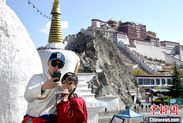4月17日，游客身著藏式元素服裝在拉薩布達(dá)拉宮觀景臺拍照留念。　李林 攝