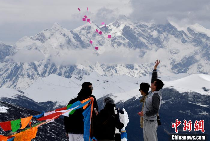 圖為5月14日，游客在西藏林芝色季拉山觀景臺拋灑“隆達”(風馬旗，藏族民眾的一種祈福方式)?！±盍?攝